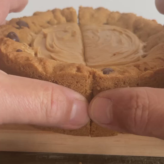 The PB Cup Beast from The Bearded Baker. Decadent peanut butter cup filling paired with Nutella, chocolate chips and peanut butter chips in a soft cookie dough being opened up to show the interior