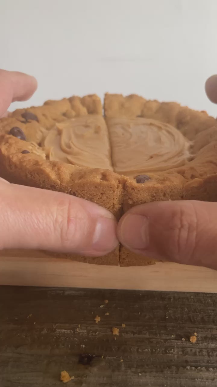 The PB Cup Beast from The Bearded Baker. Decadent peanut butter cup filling paired with Nutella, chocolate chips and peanut butter chips in a soft cookie dough being opened up to show the interior