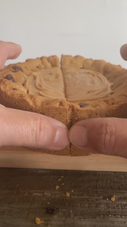 The PB Cup Beast from The Bearded Baker. Decadent peanut butter cup filling paired with Nutella, chocolate chips and peanut butter chips in a soft cookie dough being opened up to show the interior